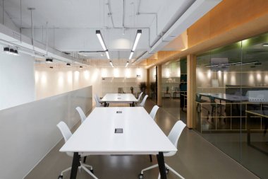 Gri duvarları, ahşap zemini, beyaz duvarları ve beyaz bilgisayar ve koyu camlı gri tabloları olan modern ofisin içinde. 3 d