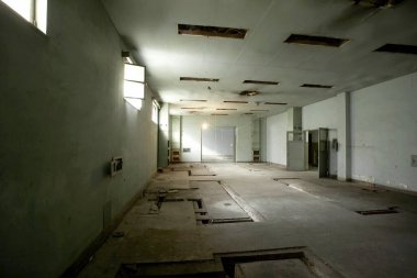 Pencereleri ve beton zemini olan terk edilmiş eski bir binanın içinde.