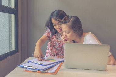 Tartışılan iki genç kadın dizüstü bilgisayar ve belgelerle çalışıyor