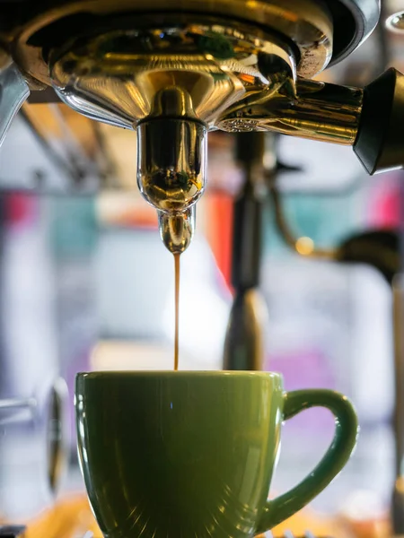 Coffee pouring from an espresso machine into a cup