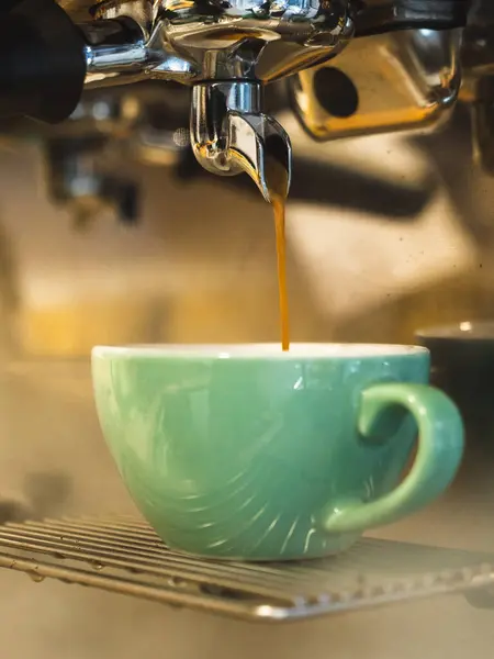 Coffee pouring from an espresso machine into a cup