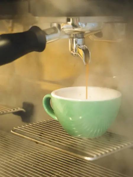 Kahve makinesinden fincana dökülüyor.