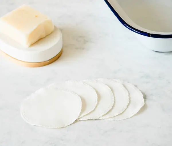 Pamuk göz pedleri art arda sergileniyor. Bir tarafında sabun çubuğu, diğer tarafında kase var.