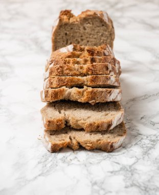 Kahverengi somun dilimlenmiş ekmek. Mermer tezgah. Dilimlerin açı görünümü