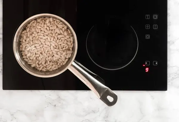 Sobanın üzerinde duran kepçenin içinde ıslak beyaz fasulye. Üst görünüm