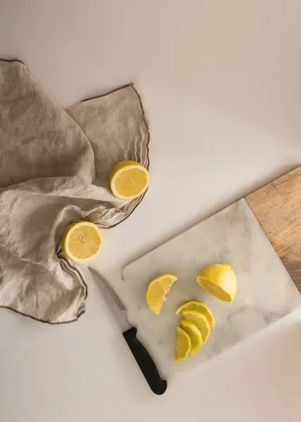 Yukarıdan görülen limonları kes. Yan tarafında bir bez ve bıçakla tahta doğrama..