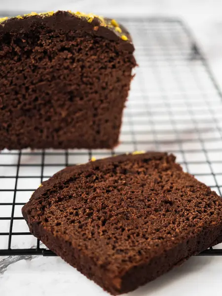 Soğutma rafında dilimlenmiş pasta ve arkasında daha büyük bir dilim pasta. Arkaplan olarak beyaz mermer tezgah