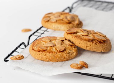 Soğutma tepsisinde beyaz arka planda bir sürü bademli kurabiye.