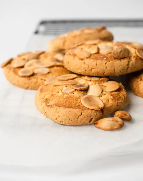 Soğutma tepsisinde beyaz arka planda bir sürü bademli kurabiye.