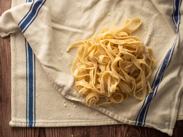 Tahta bir masada taze makarna ve mutfak örtüsü.