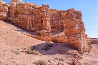 Kazakistan çölündeki dev Charyn Kanyonu. Bulutsuz mavi gökyüzü. Çerçevenin ortasında bir sürü çıkıntılı kaya var. İnsanlar olmadan. Vahşi yaşam tüm ihtişamıyla
