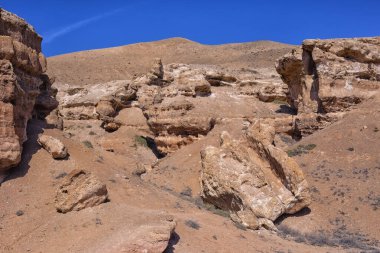 Kazakistan çölündeki dev Charyn Kanyonu. Merkezde bir sürü kaotik tuhaf sarı kaya ve bloklar ve çölde seyrek bitki örtüsü var.