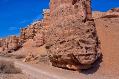 Kazakistan çölündeki dev Charyn Kanyonu. Bulutsuz mavi gökyüzü. Çerçevenin ortasında kocaman sarı çıkıntılı bir kaya. İnsanlar olmadan. Tüm ihtişamıyla yaban hayatı manzarası