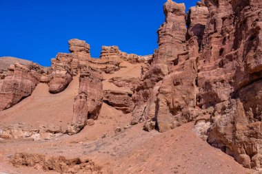Kazakistan çölündeki dev Charyn Kanyonu. Çerçevenin ortasında büyük, izole bir dağ ve kaya ince bulut tüyleriyle mavi bir gökyüzüne karşı.