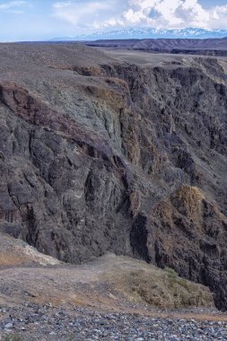 Kanyonun siyah kayaları, dağların ve bulutların arkaplanına karşı güzel taş yapılar. Taşların dokusu