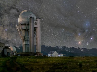 Geceleri Kazakistan 'daki Göt-Turgen Gözlemevi' ne karşı galaksinin merkezi ve karlı dağların arka planındaki Samanyolu 'na karşı. At Nebulası 'nın bir parçası ve Akrep takımyıldızından Akrep takımyıldızına kadar uzanan bir yıldız tozu serisi. 