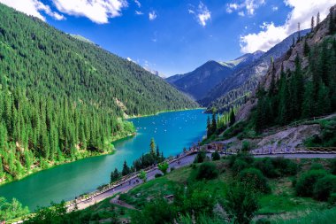 Kolsai Gölü, Almaty, Kazakistan. Mavi suyu olan dağ gölü, bir sürü teknesi olan yeşil ağaçlar, insanlar ve turistler.
