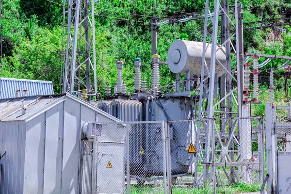 Elektrik santralinin bir kısmını yeşil ağaçların arka planına yakın çekim. Yalıtıcılar, kablolar, elektrik, tabela 