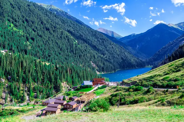 Kolsai Gölü, Almaty, Kazakistan. Dağlar arasında mavi suyu olan eşsiz bir dağ gölü. Küçük evler ve dağ zirveleri. Yukarıdan görüntüle