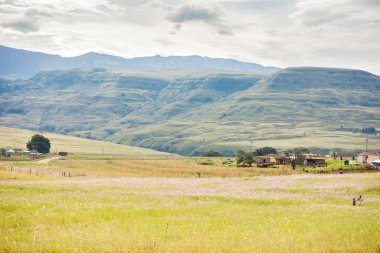 Kwa-Zulu Natal 'daki Drakensburg dağlarında bulutlu gökyüzü olan kır evleri.