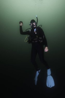 Dişi bir scuba dalgıcı güvenlik durağında bir yüzey şamandırasının makarasını tutuyor.