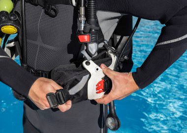 Scuba dalgıcının ağırlık cebini havuzun yanındaki BCD cebine soktuğu yakın plan..