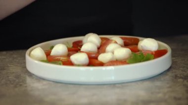 Mozzarella peynirli toplar ve kırmızı vişneli domates, Turning. Seçici odaklanma. Mini mozzarella soslu kanepeler, domatesler kiraz ve soya soslu fesleğen..