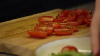 Salata için vişneli domates doğrayan kadın. Dişi eller tahtada kiraz domatesleri kesiyor..