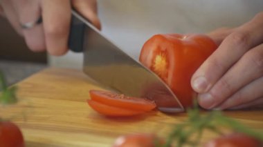 Havuç ve erkek el ahşap kesme tahtası salata sağlıklı gıda mutfak tablo için domates kesim Dilimleme adam el atış kapatın. Yan görünüm.