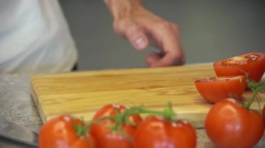 Havuç ve erkek el ahşap kesme tahtası salata sağlıklı gıda mutfak tablo için domates kesim Dilimleme adam el atış kapatın. Yan görünüm.