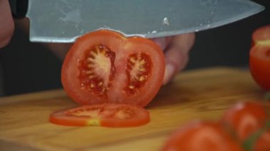 Havuç ve erkek el ahşap kesme tahtası salata sağlıklı gıda mutfak tablo için domates kesim Dilimleme adam el atış kapatın. Yan görünüm.