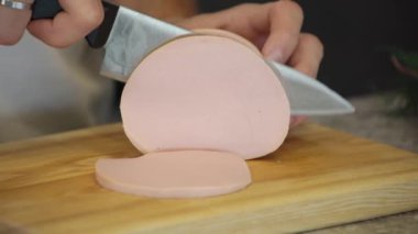 Ahşap tahtada Haşlanmış Sosis Kesen Aşçı Adam.