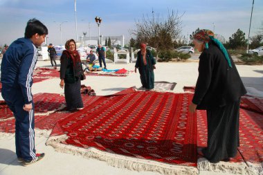 Ashgabat, Türkmenistan - Mart 15.2020: İnsanlar Doğu pazarından geleneksel süs eşyasıyla geleneksel Türkmen el yapımı halılar satın alıyorlar.