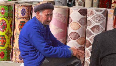 Ashgabat, Türkmenistan pazarı - Mart 15.2020: Bilinmeyen bir halı satıcısı alıcıyla konuşuyor.