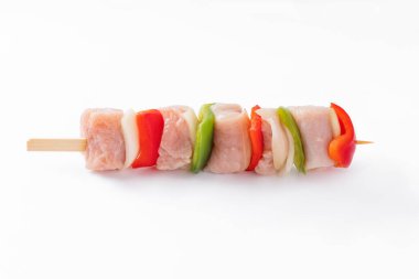 Top view.Uncooked mixed meat skewer with peppers.Raw turkey skewers with vegetables, peppers, onions on a white background.Skewers with pieces of raw meat, red, and green pepper, on white background.