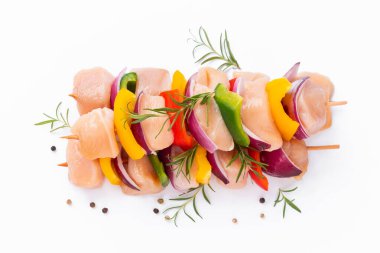 Skewers with pieces of raw meat, red, yellow and green pepper.Top view.Uncooked mixed meat skewer with peppers.Raw chicken skewers with vegetables, peppers, onions, on a white background.