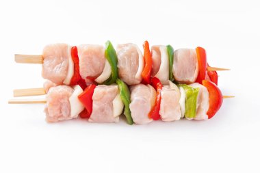 Top view.Uncooked mixed meat skewer with peppers.Raw turkey skewers with vegetables, peppers, onions on a white background.Skewers with pieces of raw meat, red, and green pepper, on white background.