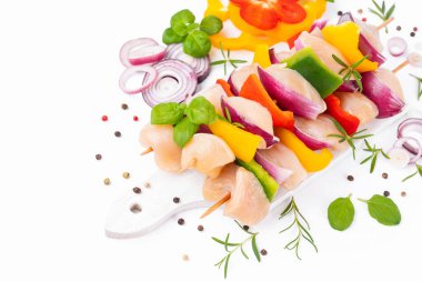 Uncooked mixed meat skewer with peppers.Raw chicken skewers with vegetables, peppers, onions, on a white background.Skewers with pieces of raw meat, red, yellow and green pepper.Top view.