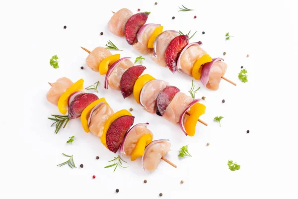 Chicken Skewers breast fillet meat.Raw chicken meat skewers with vegetables,plums,yellow pepper,onions,with spices,herbs white background.Uncooked meat skewer.Skewers with pieces of raw meat.Top view.