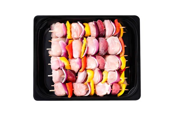 Raw uncooked Chicken meat, kebab on skewers.Raw chicken leg meat skewers with vegetables, plums, peppers, onions, in a tray on a white background.Top view.Close-up.