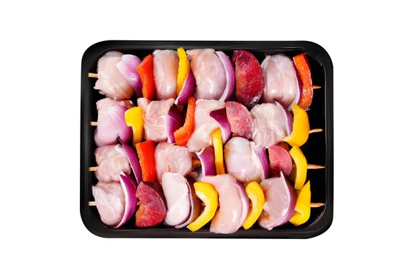 Raw uncooked Chicken meat, kebab on skewers.Raw chicken leg meat skewers with vegetables, plums, peppers, onions, in a tray on a white background.Top view.Close-up.