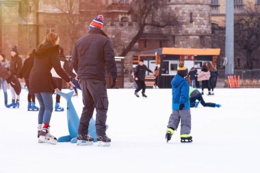 04.01.2022.Budapest.Winter sports.Family winter sport.Holiday and seasonal concept.Activity,Adult,Child,Childhood, Daughter.Happy little boy and girl learning to skate in winter.Hobbies and Leisure.
