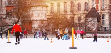 04.01.2022 Budapeşte. Çocuklar ve yetişkinler kış günü açık havada buz pateni pistine giderler. Aile kış sporu. Yumuşak, seçici odaklanma. Açık hava. Kış sporu..