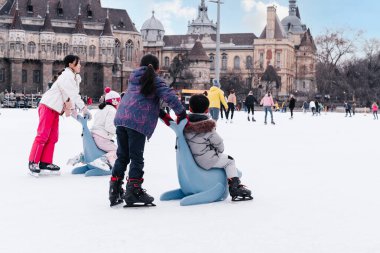 04.01.2022.Budapest.Family winter sport.Holiday and seasonal concept.Happy little boy and girl learning to skate in winter.Hobbies and Leisure.Winter sports.Activity,Adult,Child,Childhood, Daughter.