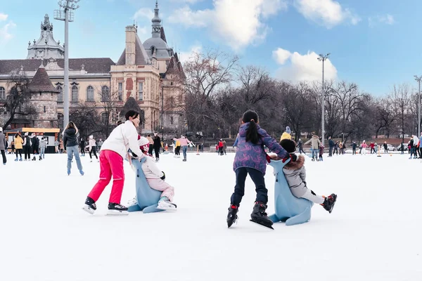 04.01.2022.Budapest.Winter sports.Family winter sport.Holiday and seasonal concept.Activity,Adult,Child,Childhood, Daughter.Happy little boy and girl learning to skate in winter.Hobbies and Leisure.