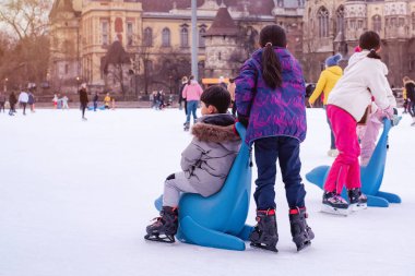 04.01.2022.Budapest.Winter sports.Family winter sport.Holiday and seasonal concept.Activity,Adult,Child,Childhood, Daughter.Happy little boy and girl learning to skate in winter.Hobbies and Leisure.