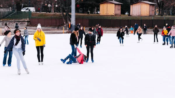 04.01.2022.Budapest.Children and adults are skating on a winter day at an outdoor skating rink. A friend helps a girl to stand up, who fell down while skating.Family winter sport.Soft,Selective focus.