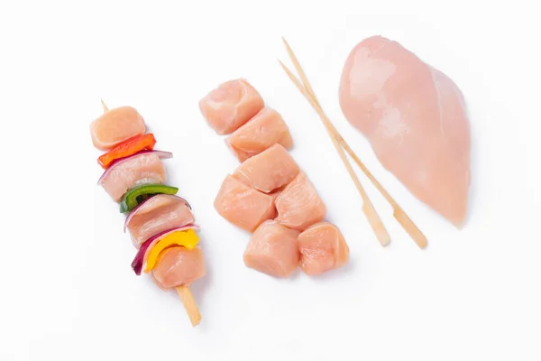 Raw chicken skewers with vegetables, peppers,onions,white background.Chicken Skewers breast fillet meat.Uncooked meat skewer with peppers.Skewers with pieces of raw meat,red,yellow pepper.Top view.