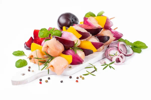 Skewers with pieces of raw meat.Top view.Chicken Skewers breast fillet meat.Raw chicken meat skewers with vegetables,plums,yellow pepper,onions,with spices,herbs white background.Uncooked meat skewer.