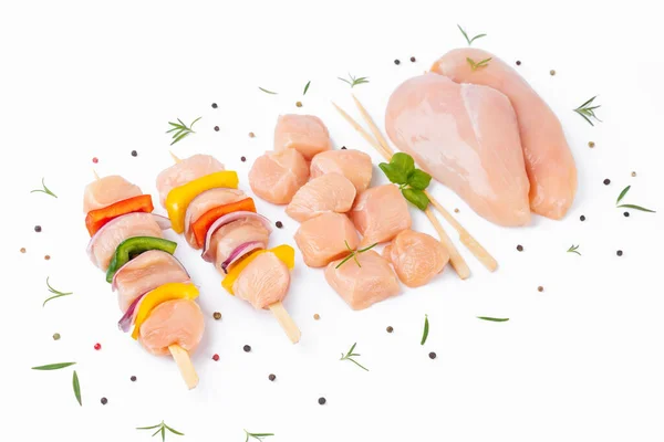 Raw chicken skewers with vegetables, peppers,onions,white background.Chicken Skewers breast fillet meat.Uncooked meat skewer with peppers.Skewers with pieces of raw meat,red,yellow pepper.Top view.